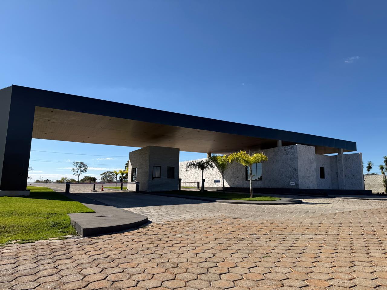 Portaria do condomínio Estância das Águas, com cobertura arquitetônica em concreto escuro e revestimento em pedra travertino